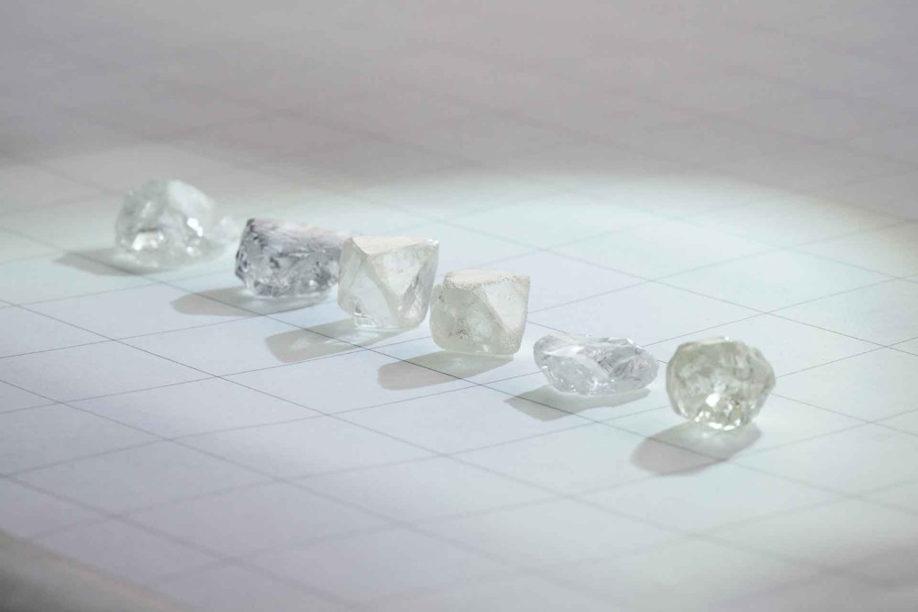 six natural diamonds lined up on a quadricular paper sheet