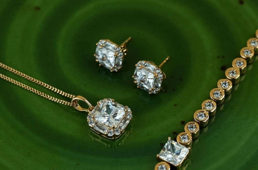 A custom diamond pendant with matching earrings and a bracelet laid on a green surface