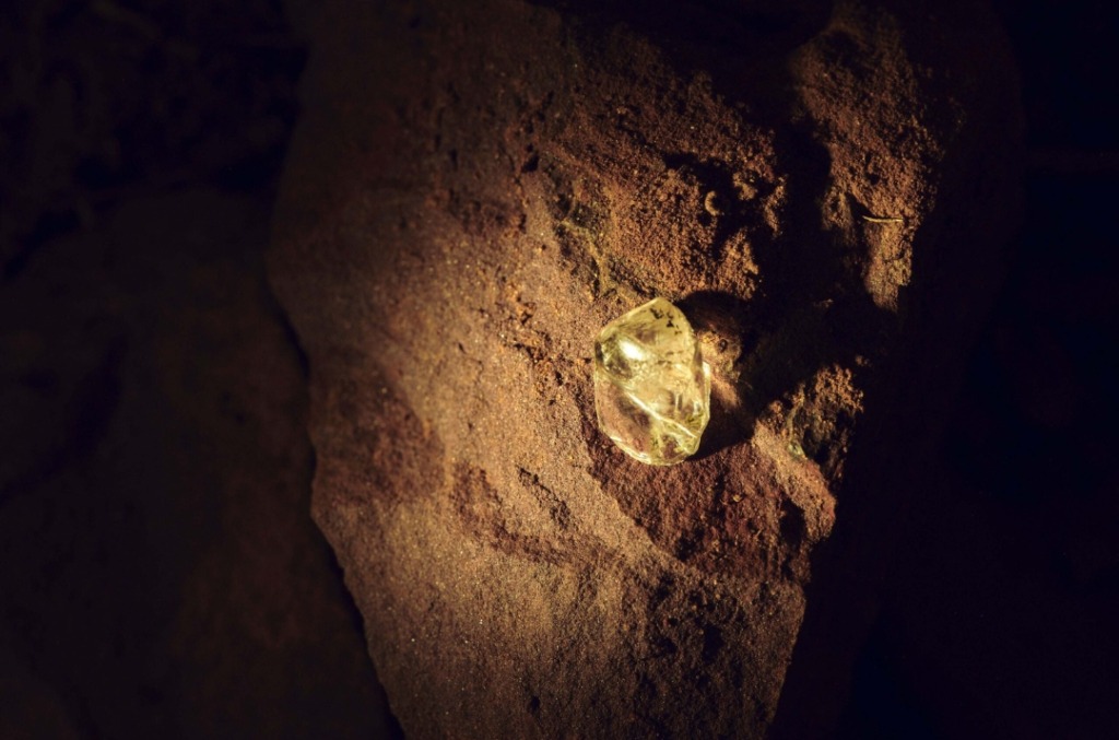 Rough yellow diamond against a rock