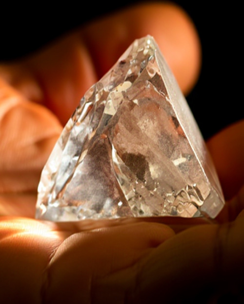 A palm holding a raw natural diamond
