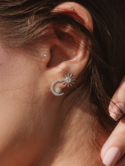 Close up of a woman's ear featuring diamond earrings on both first and second piercings