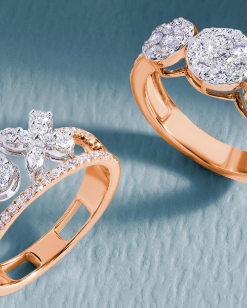 Two diamond and gold rings on a pale blue surface