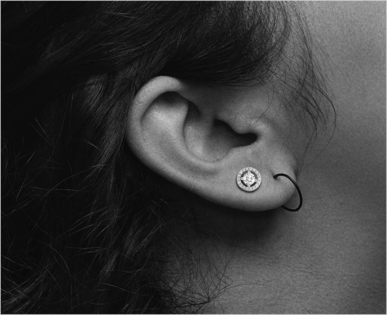Close up of an ear with a diamond earring in the second piercing