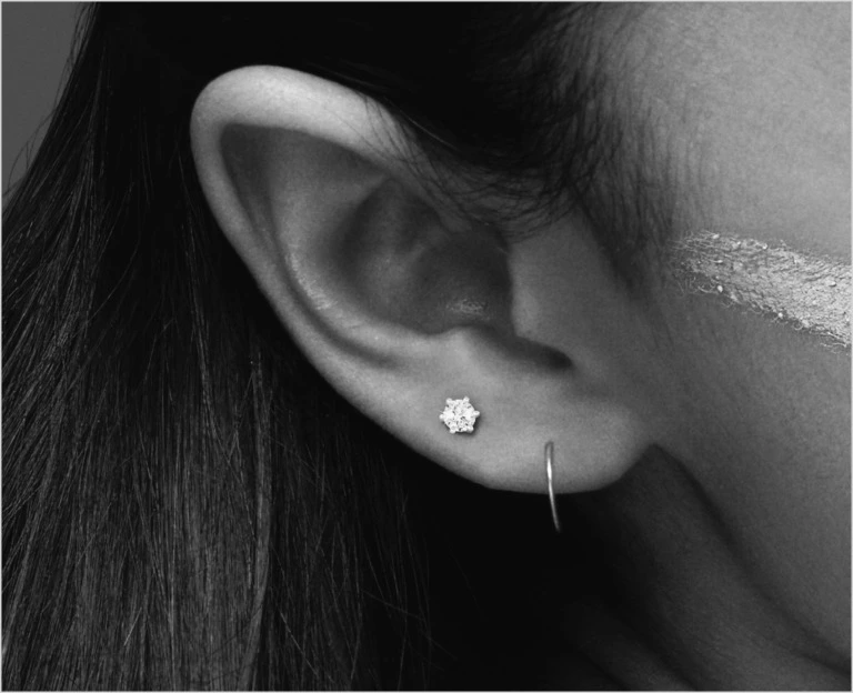 Close up of an ear with a diamond stud in the second piercing