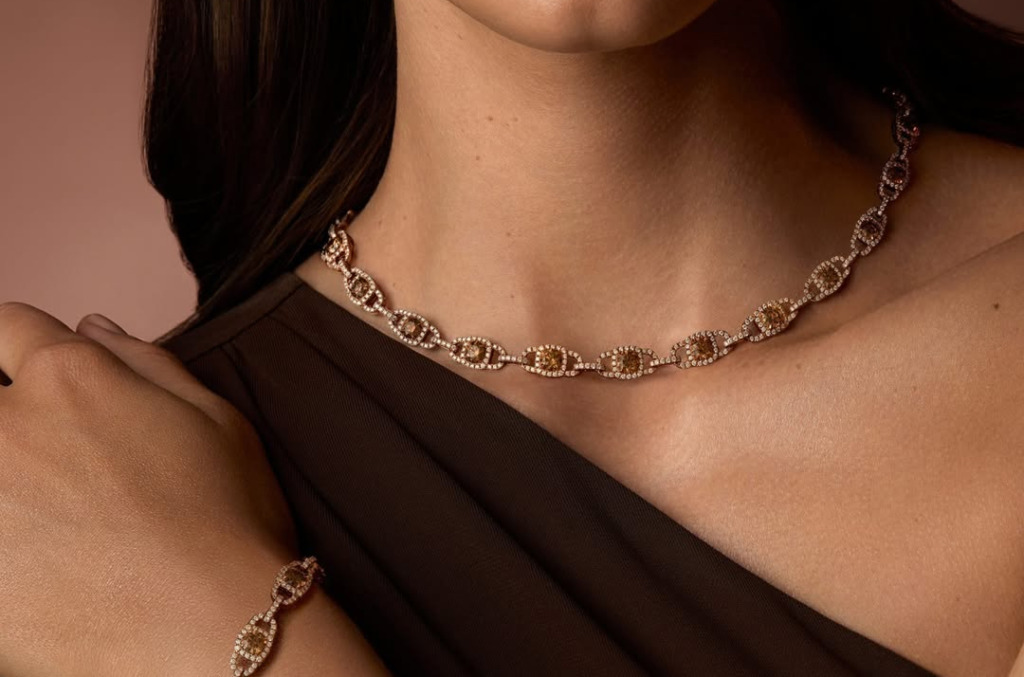 Close up of a woman in a brown dress wearing matching whiskey toned diamond jewellery