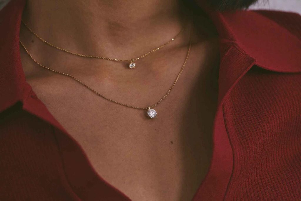 Close up of a woman wearing layered chains with diamond pendants