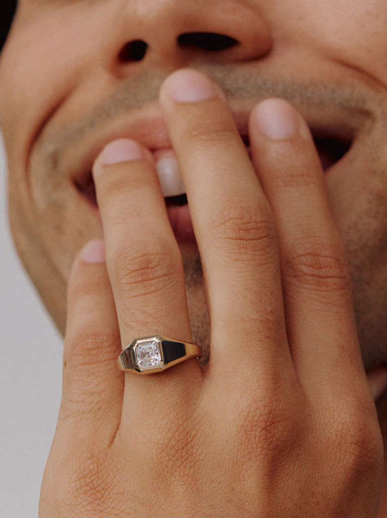 Close up of a man's fingers featuring a solitaire bezel diamond ring