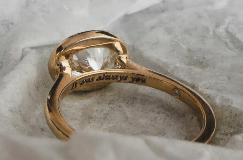 Close up of a customised engagement ring engraved with "It was always you"