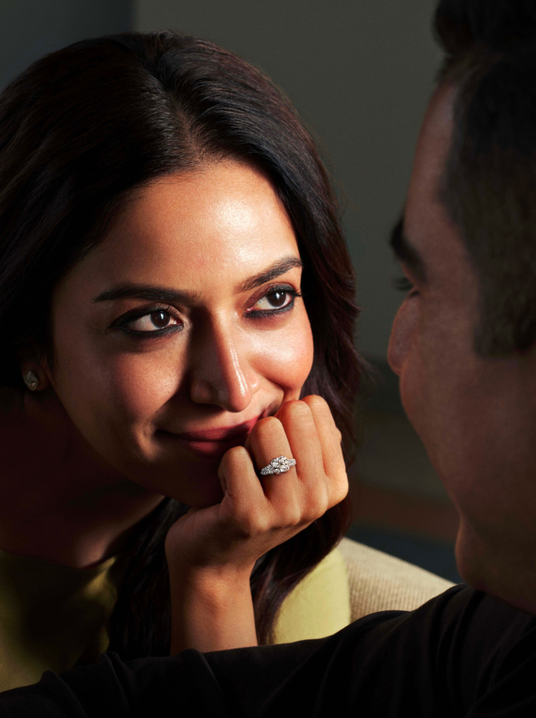 A woman wearing a solitaire natural diamond ring, gazing at her husband
