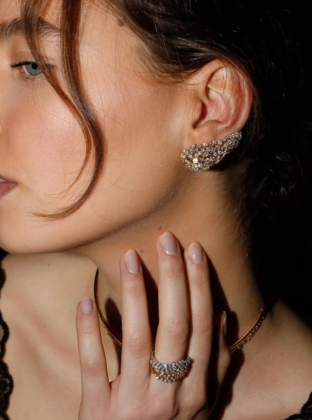 Woman wearing a diamond ear crawler and a diamond ring