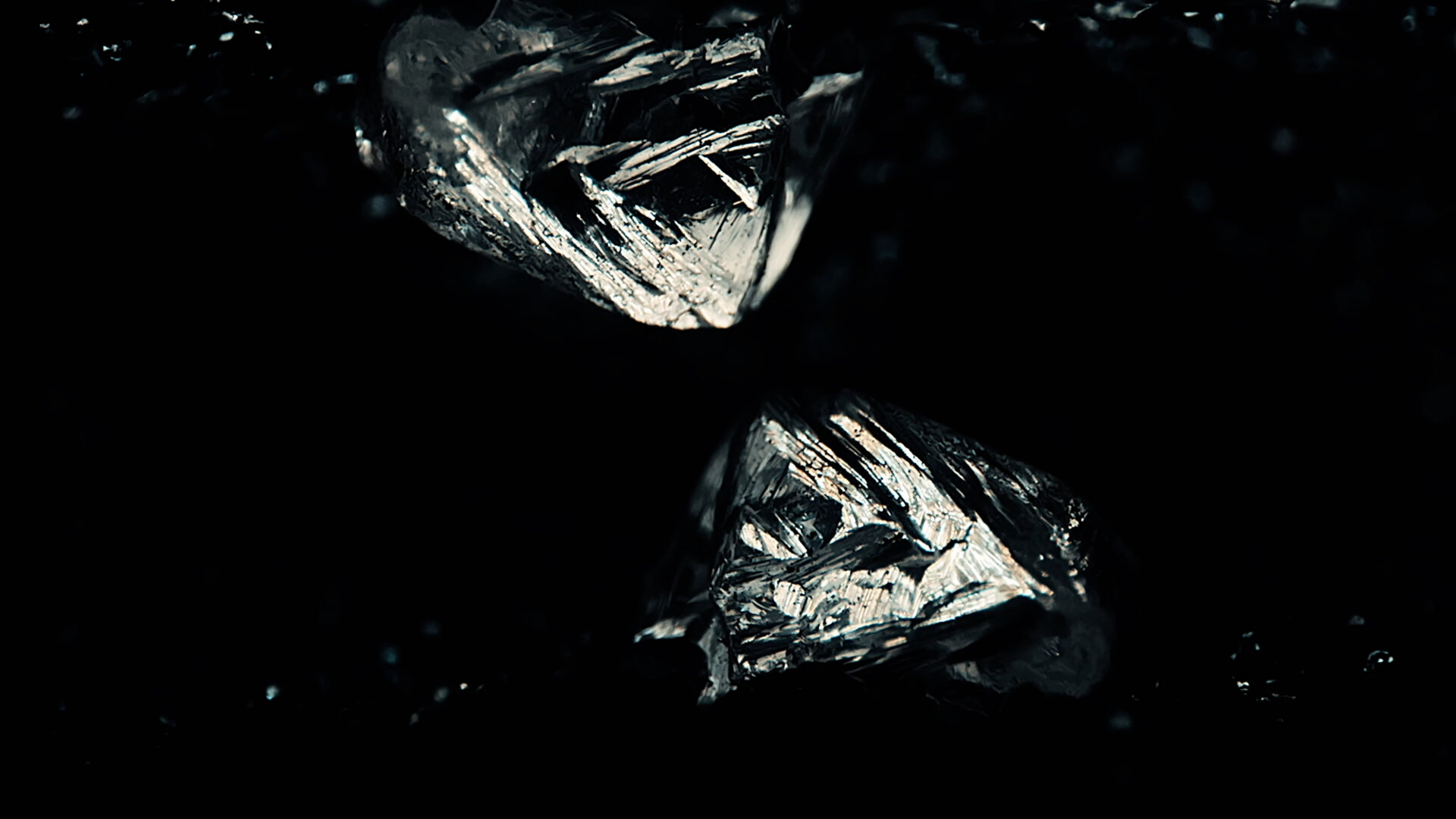 Close-up of raw, uncut natural diamonds with rugged edges in a dark background.