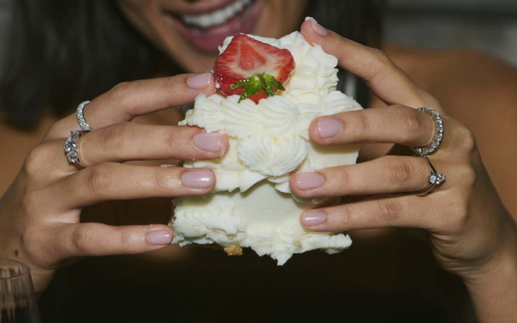 Hands with diamond rings on holding cake