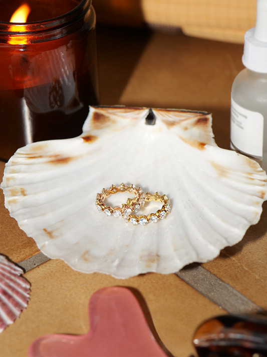 Two diamond rings sat in a scallop shell
