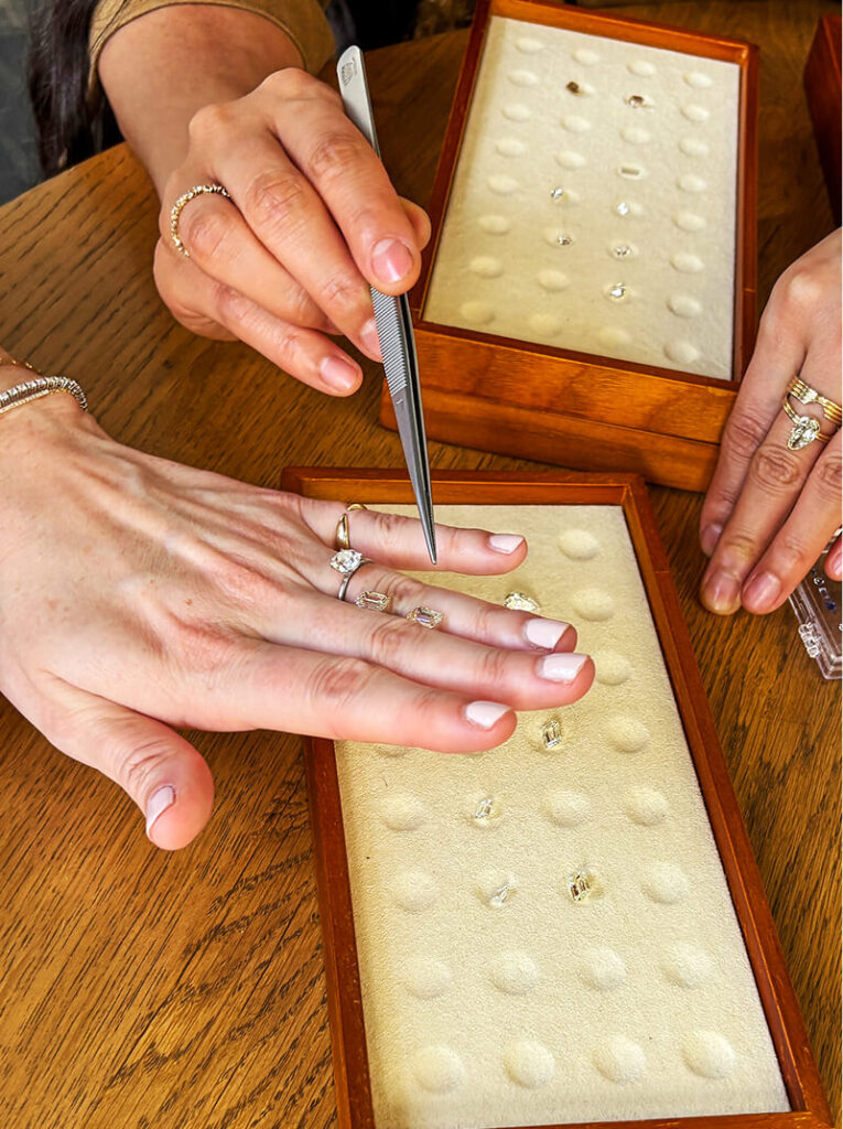 Hands looking at polished and set diamonds with tweezers