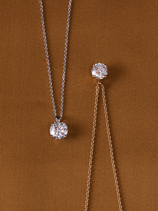 Two white diamond pendant necklaces on brown background