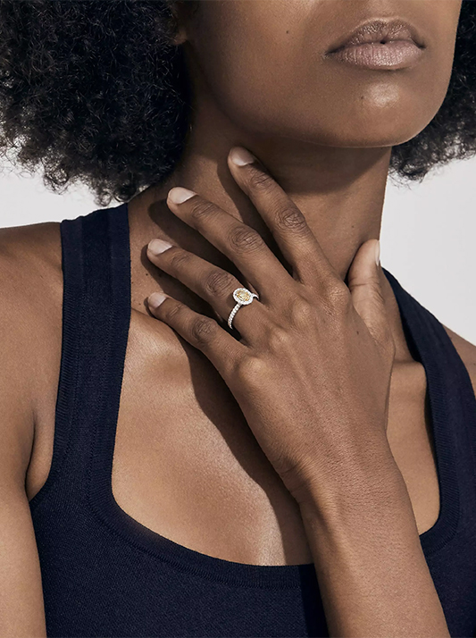 Black female wearing yellow diamond on ring finger
