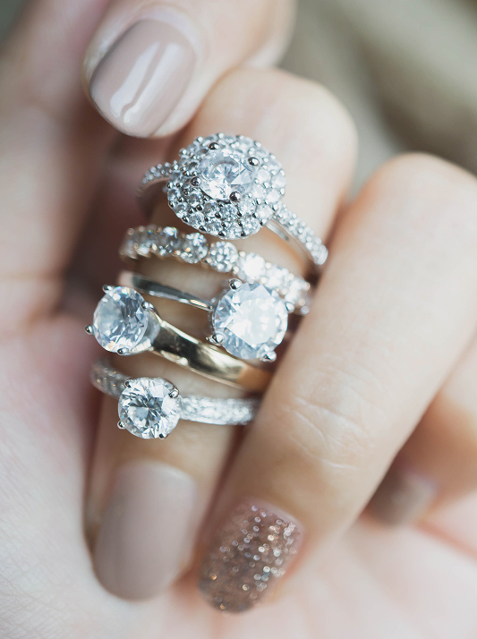 A variety of natural diamond engagement rings stacked on a finger