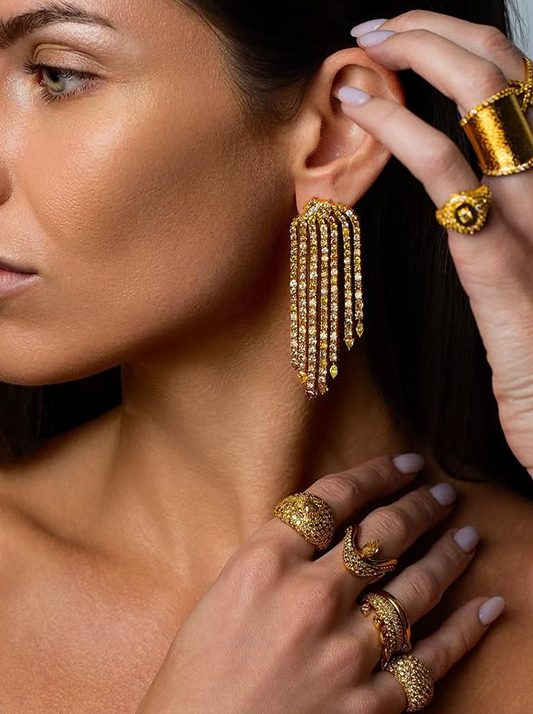 A woman wearing gold earrings and rings, all featuring Whiskey Desert diamonds