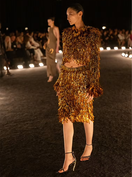 Model walking the runway in metallic gold and bronze dress reflecting the rich, warm tones of Whiskey Desert diamonds.
