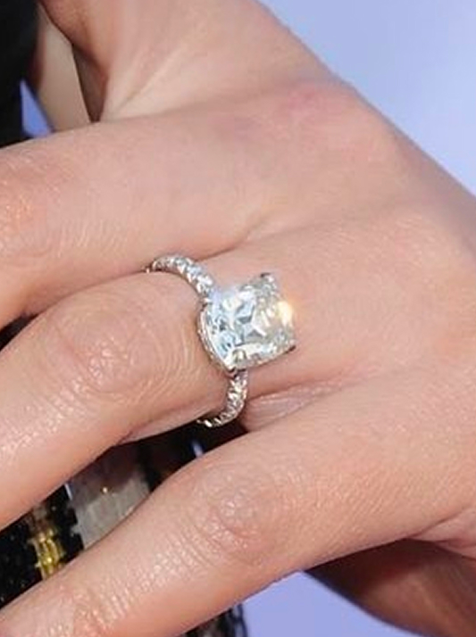 Chrissy Teigan's engagement ring featuring a cushion-cut natural diamond of five to six carats, set on a pavé band