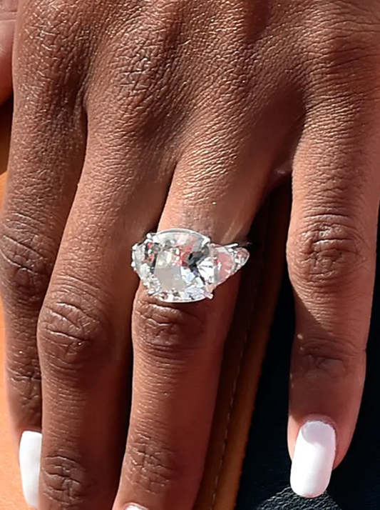 Ciara’s natural diamond engagement ring with a flawless 16-carat round brilliant-cut center stone, flanked by four side stones: trapezoid-shaped diamonds on either side and pear-shaped diamonds at each outer edge