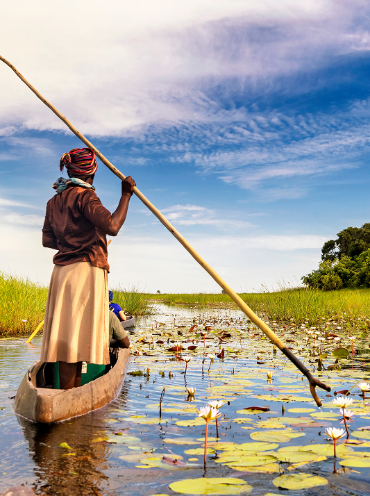 Woman guiding a mokoro canoe through the Okavango Delta’s wetlands