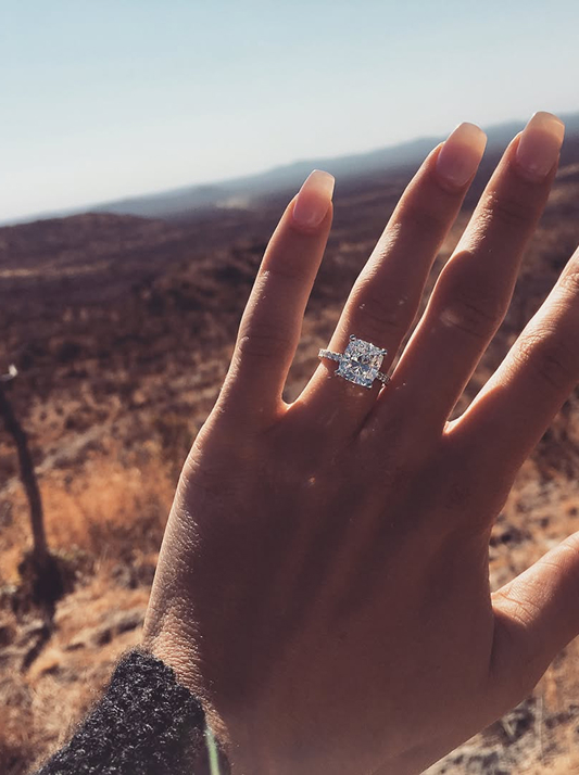 Close-up of Keleigh Sperry’s hand showing her square-cut natural diamond engagement ring against the South African landscape.