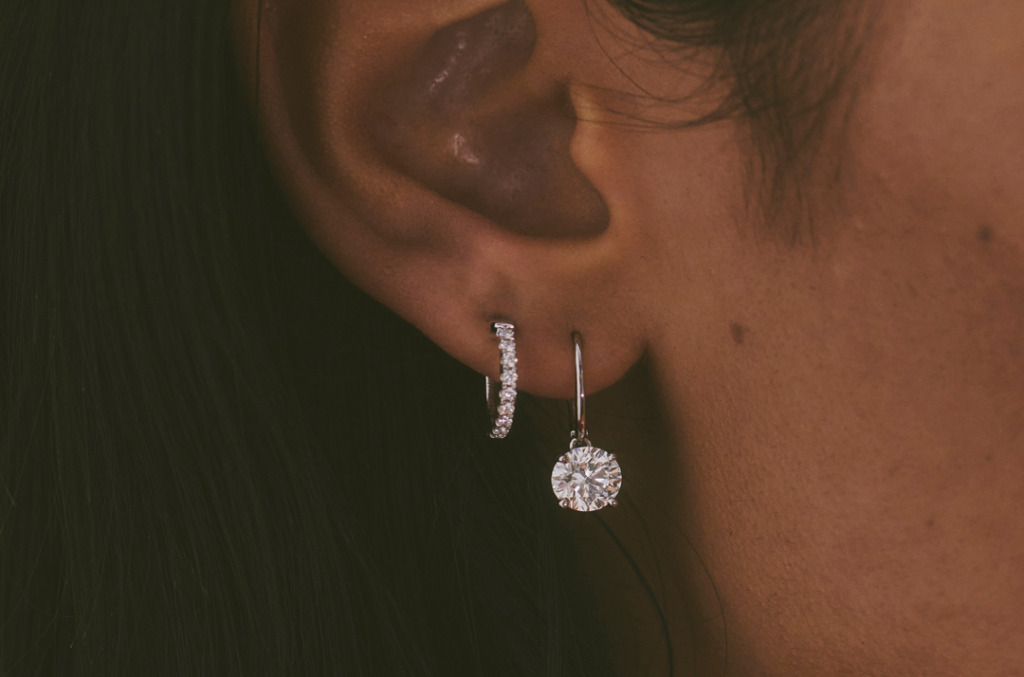 An ear featuring a diamond encrusted hoop earring and drop earring 