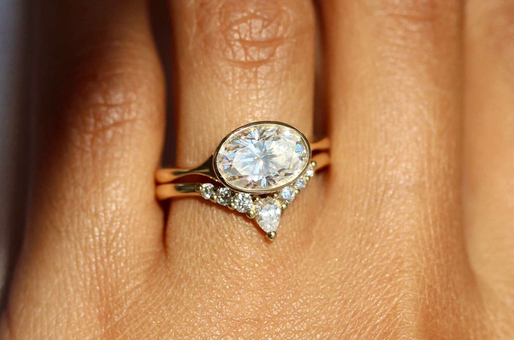 A bezel-set oval diamond ring and wishbone style wedding band 