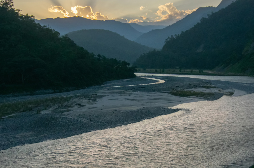 A winding river flowing through a mountainous landscape at sunset, evoking the ancient Indian riverbeds where the world’s earliest natural diamonds were first discovered.