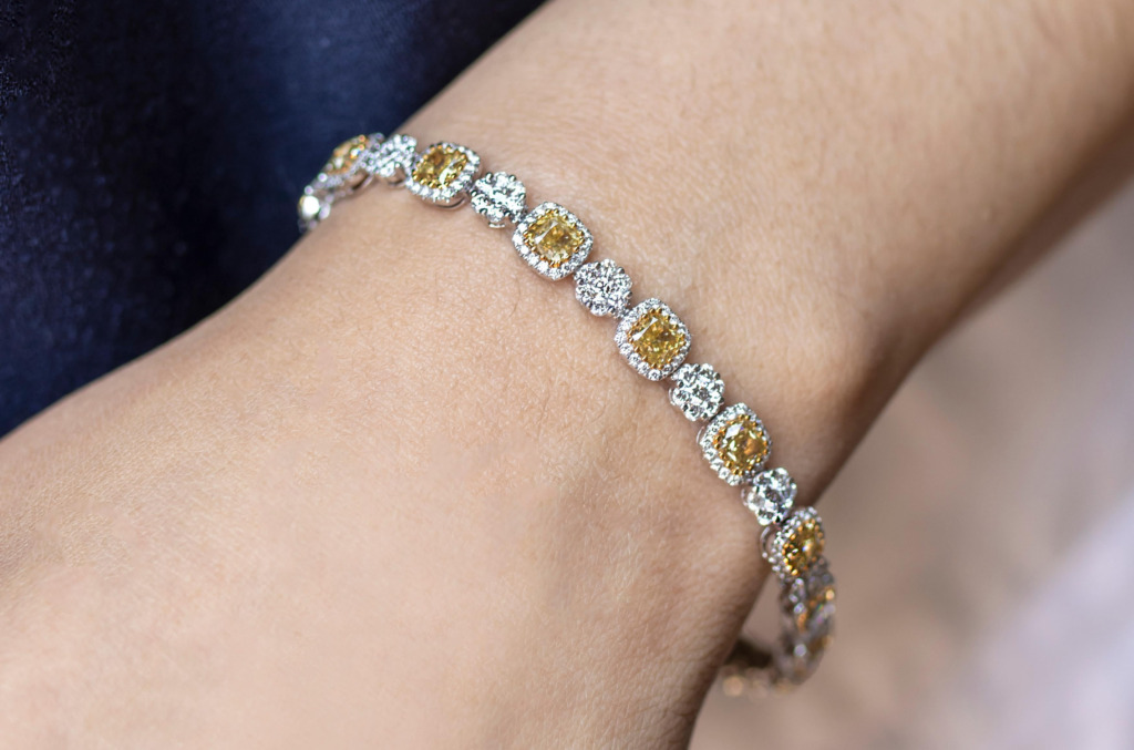 Cushion-cut diamond bracelet featuring alternating halo-set diamonds in a repeating link design, worn on the wrist.