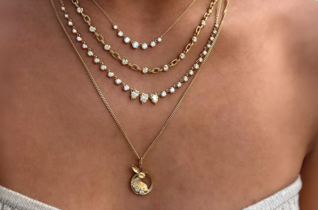 a graduated diamond line, a link chain with diamond stations and a charm pendant layer at different lengths