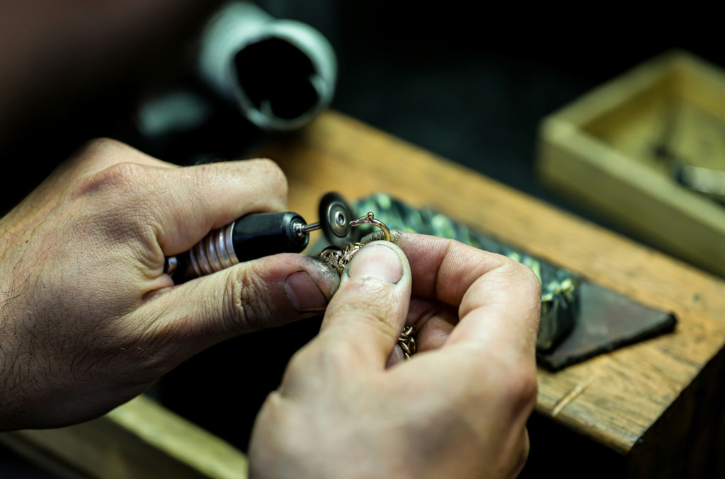 a jeweler working creating a diamond necklace with tools