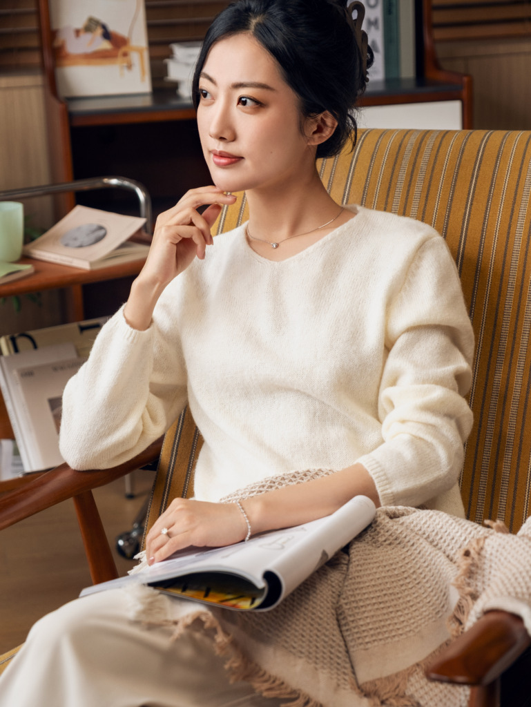 温暖的室内光线下，女性翻阅书籍，佩戴钻石戒指与腕间手链。